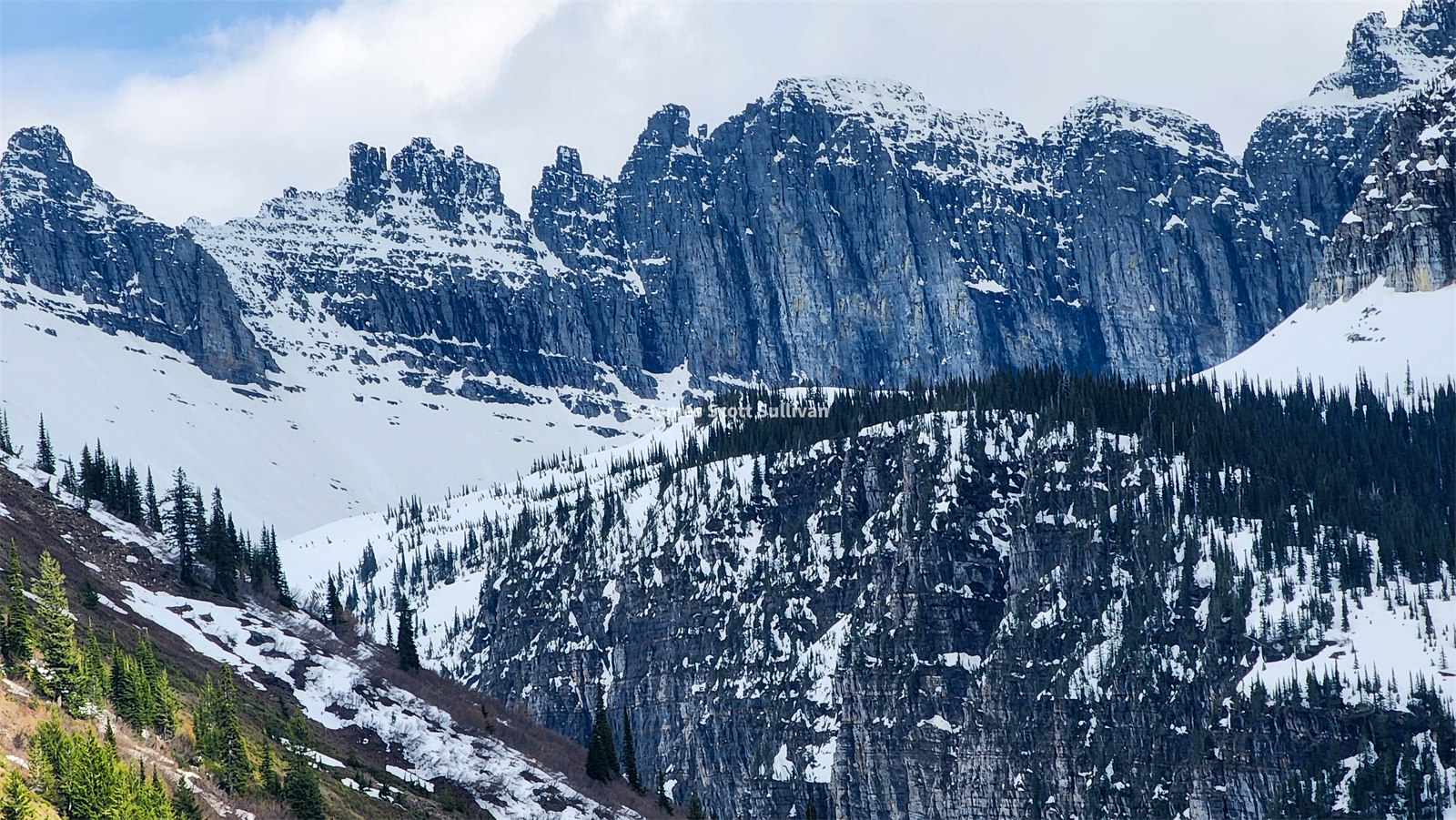 Steep glacier-cut wall of snow and rock in Many Glacier.