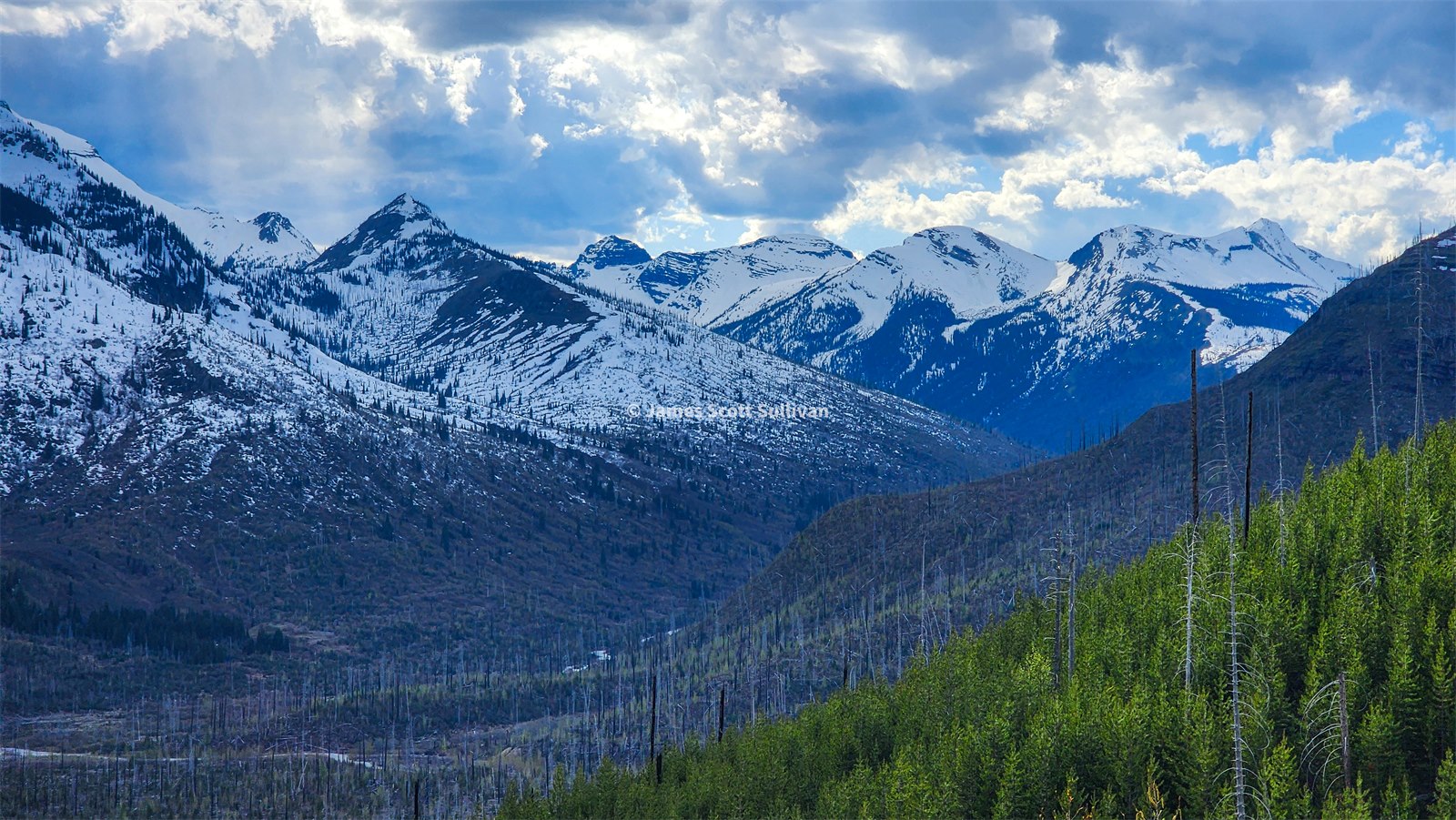 Snow-covered peaks and burned slopes above Glacier National Park.
