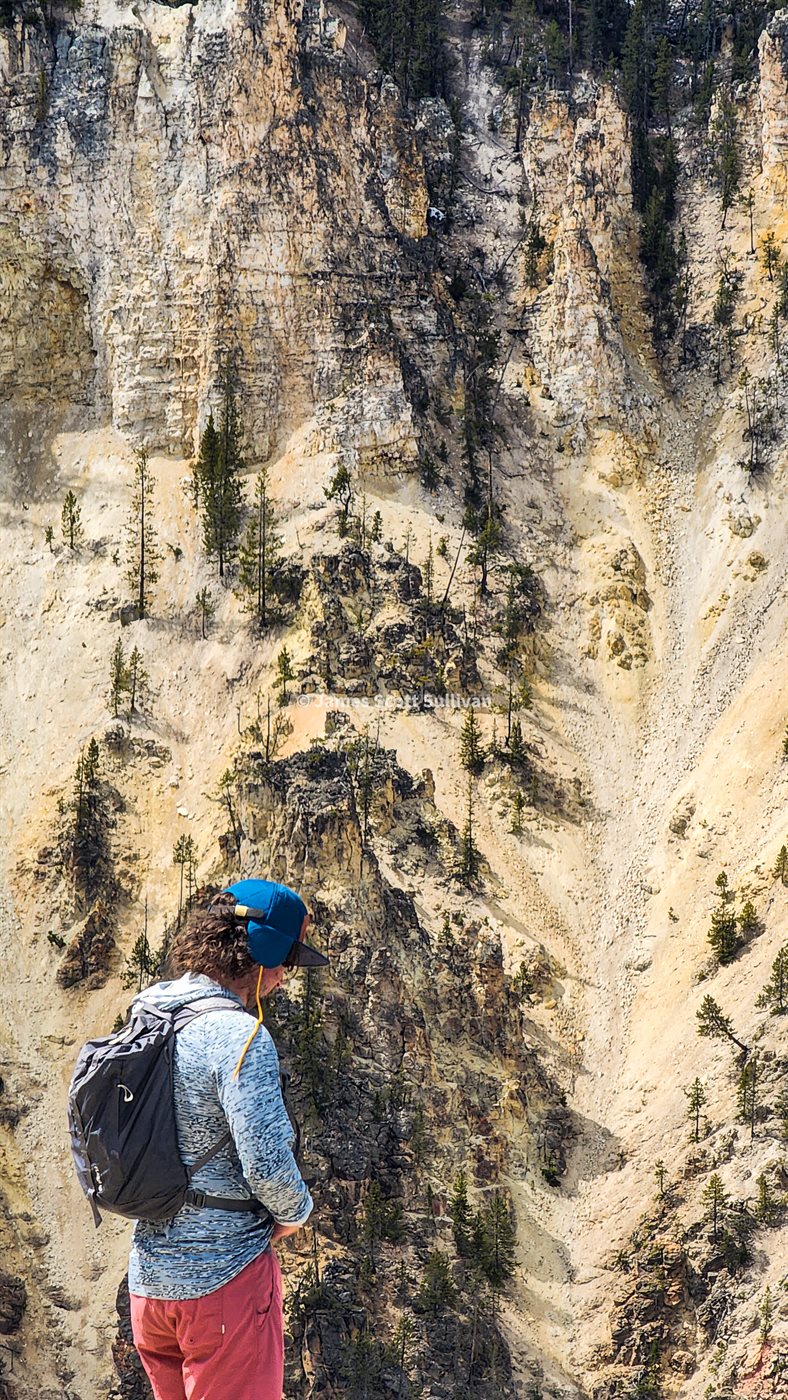 A hiker standing beneath pale cliffs in Yellowstone country.