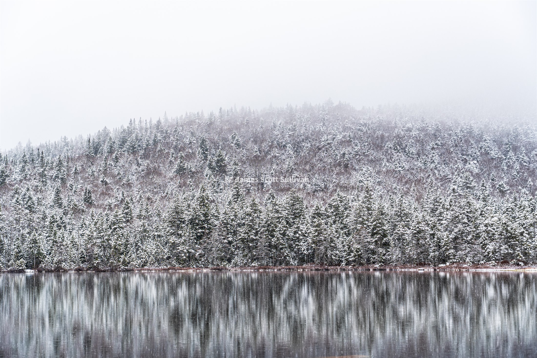 Watermarked preview of Lonesome Lake during a calm spring snowfall on the way up to Kinsman Ridge in New Hampshire.